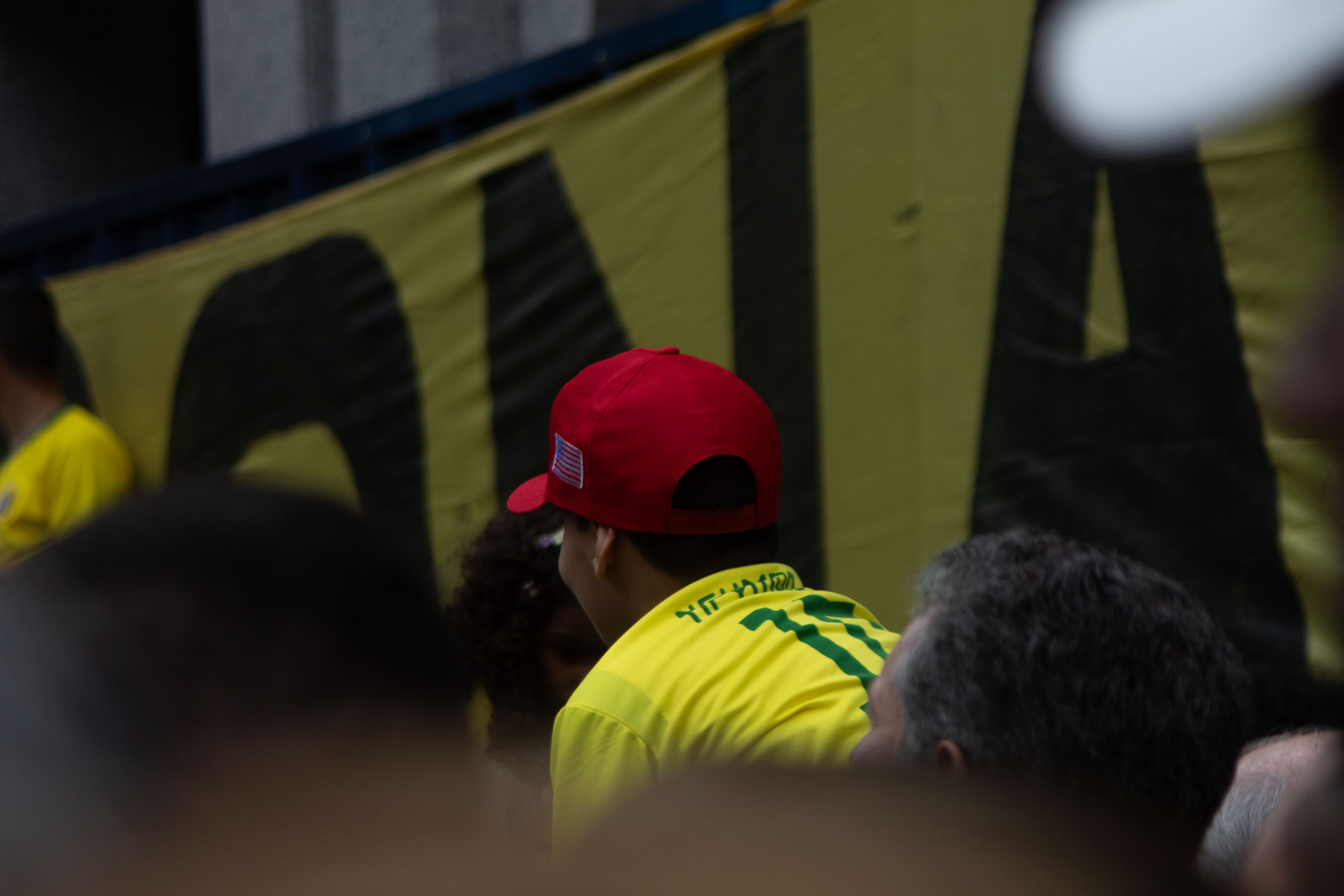 Um menino em cima de seu pai que gritava com a camisa do neymar e o boné da campanha do presidente Donald Trump / Foto: Rafael Pessoa
