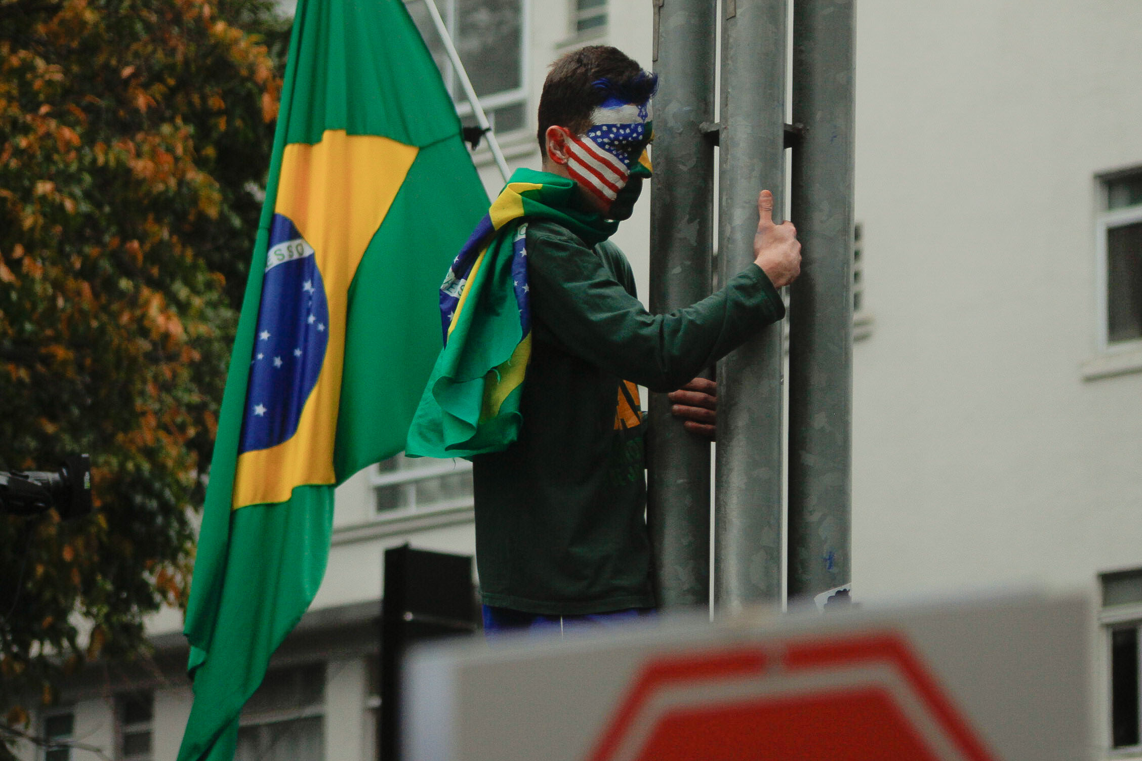 Manifestante que tinha o rosto pintado com as bandeiras de Israel, Estados Unidos e Brasil com uma bandeira do brasil em seu ombro e “Anistia Já” escrito em seu peito / Foto: Rafael Pessoa