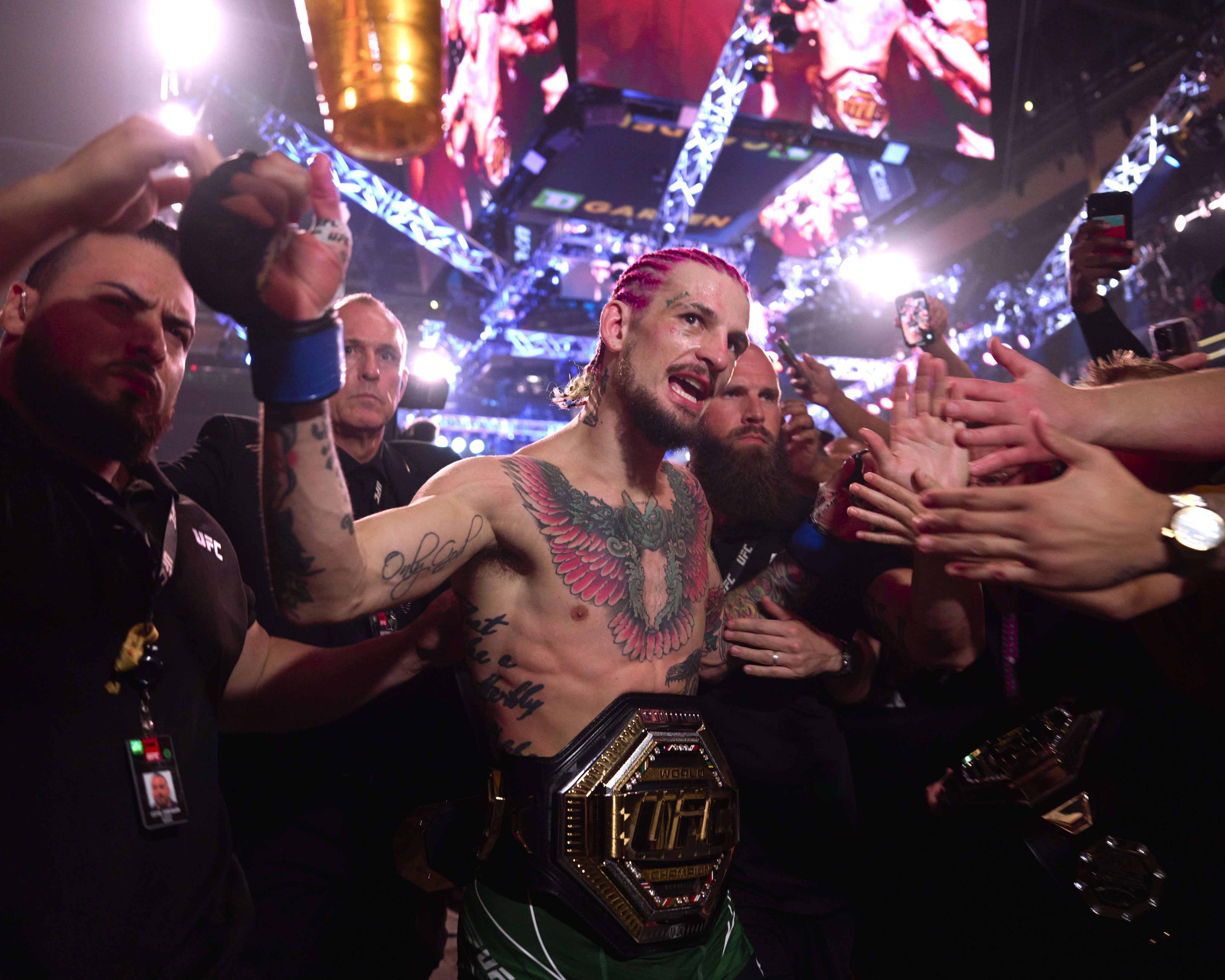 Sean O’Malley saindo do octógono e cumprimentando os fãs com seu novo cinturão. (Foto: Cooper Neill | Crédito: Zuffa LLC via Getty Images | Reprodução: @UFC)