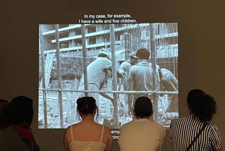 Cinco pessoas sentadas assistindo um filme em um telão 