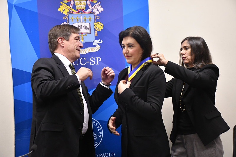 Tebet recebe o Colar de Mérito Acadêmico pelo reitor da PUC-SP, Vidal Serrano Nunes Júnior, e pela  vice-reitora, Clara Reis Longhi. Foto: Divulgação/Jornal da PUC-SP
