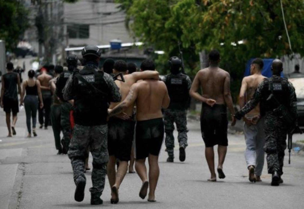 Suspeitos presos são levados por policiais durante a Operação Contenção para fora da favela Vila Cruzeiro, no complexo da Penha, Rio de Janeiro