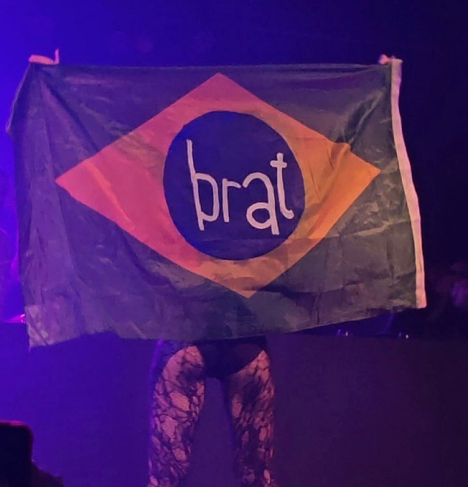 Charli xcx estendendo bandeira do Brasil com o nome do seu último álbum.