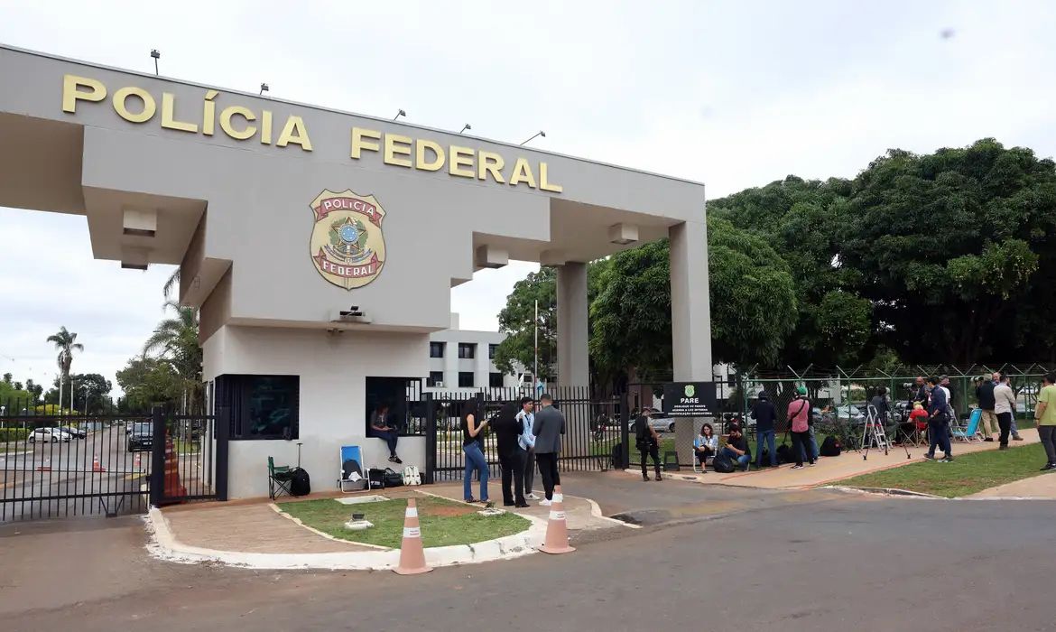 A imagem mostra a fachada da polícia federal à luz do dia
