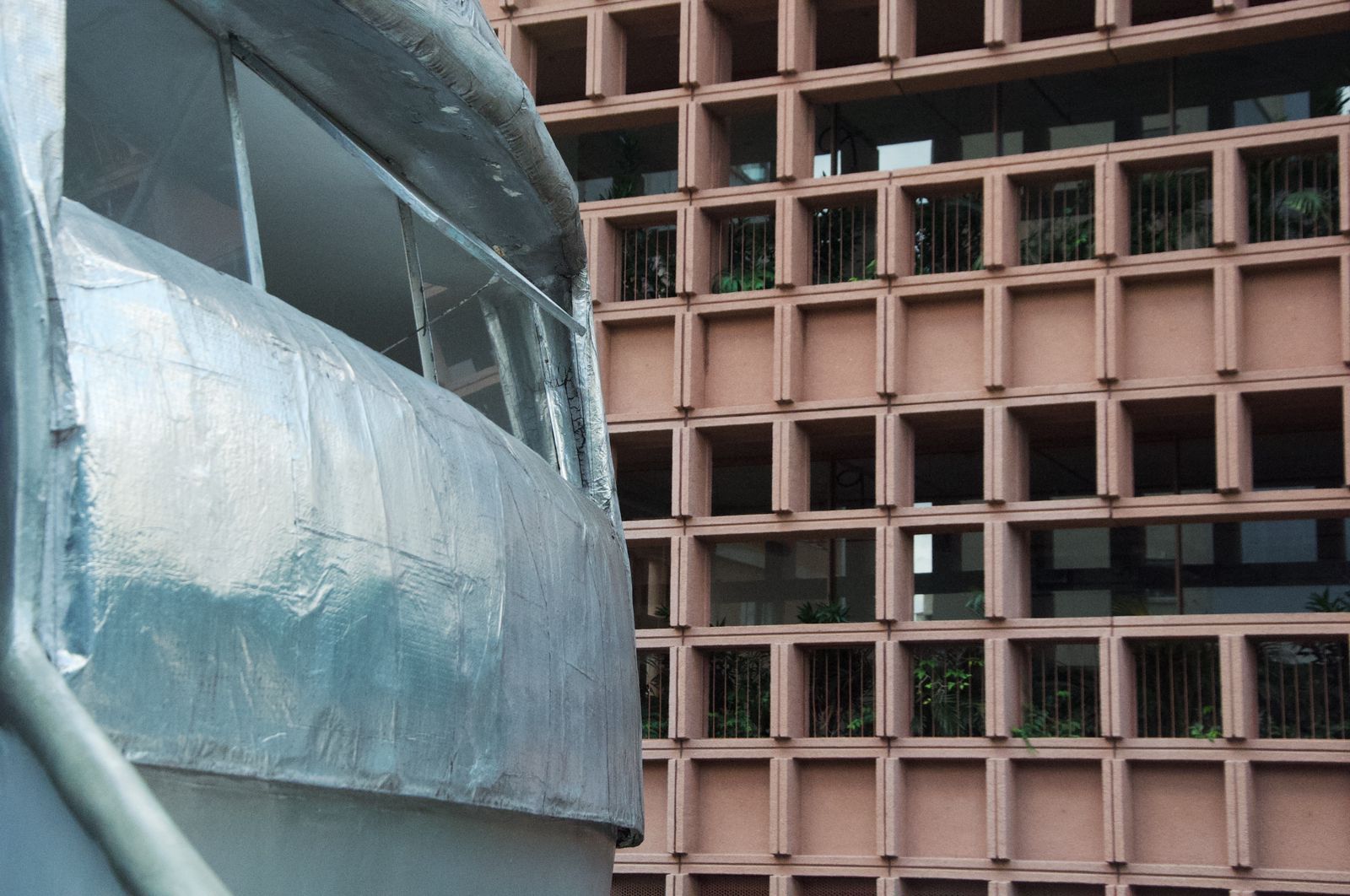Contraste entre a estética radical da Casa Bola e a geometria rígida da arquitetura tradicional ao lado.